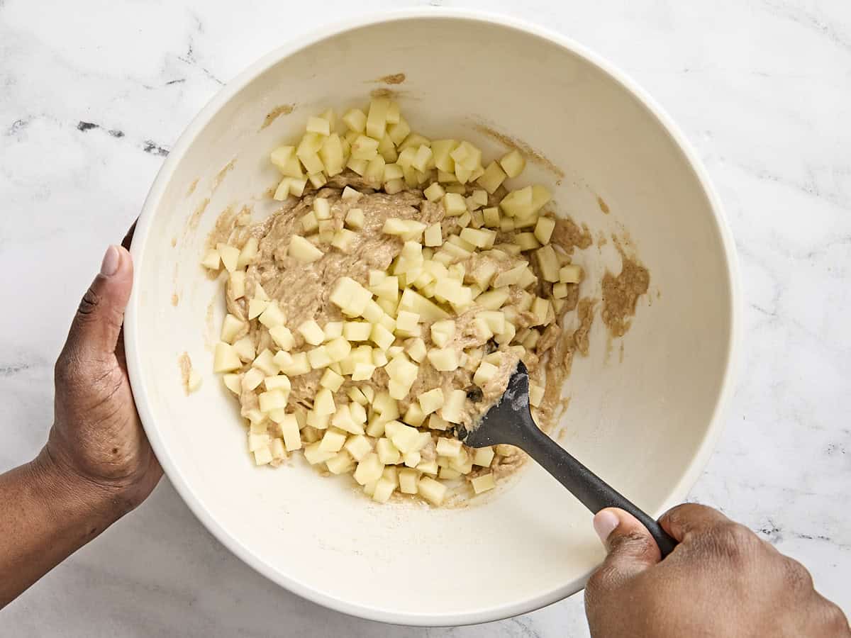 Apples added to the batter for apple cinnamon muffins in a bowl.