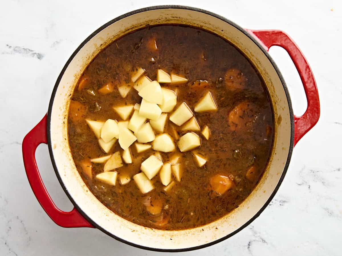 Potatoes added to beef stew in a dutch oven.