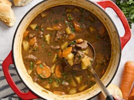 Overhead view of beef stew in a dutch oven with a ladle.