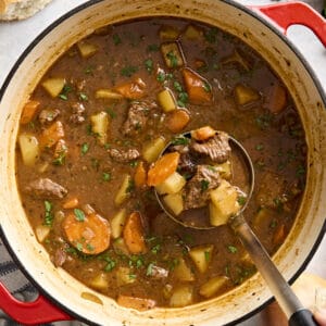 Overhead view of beef stew in a dutch oven with a ladle.