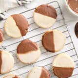 Overhead view of black and white cookies on a wire rack.