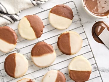 Overhead view of black and white cookies on a wire rack.