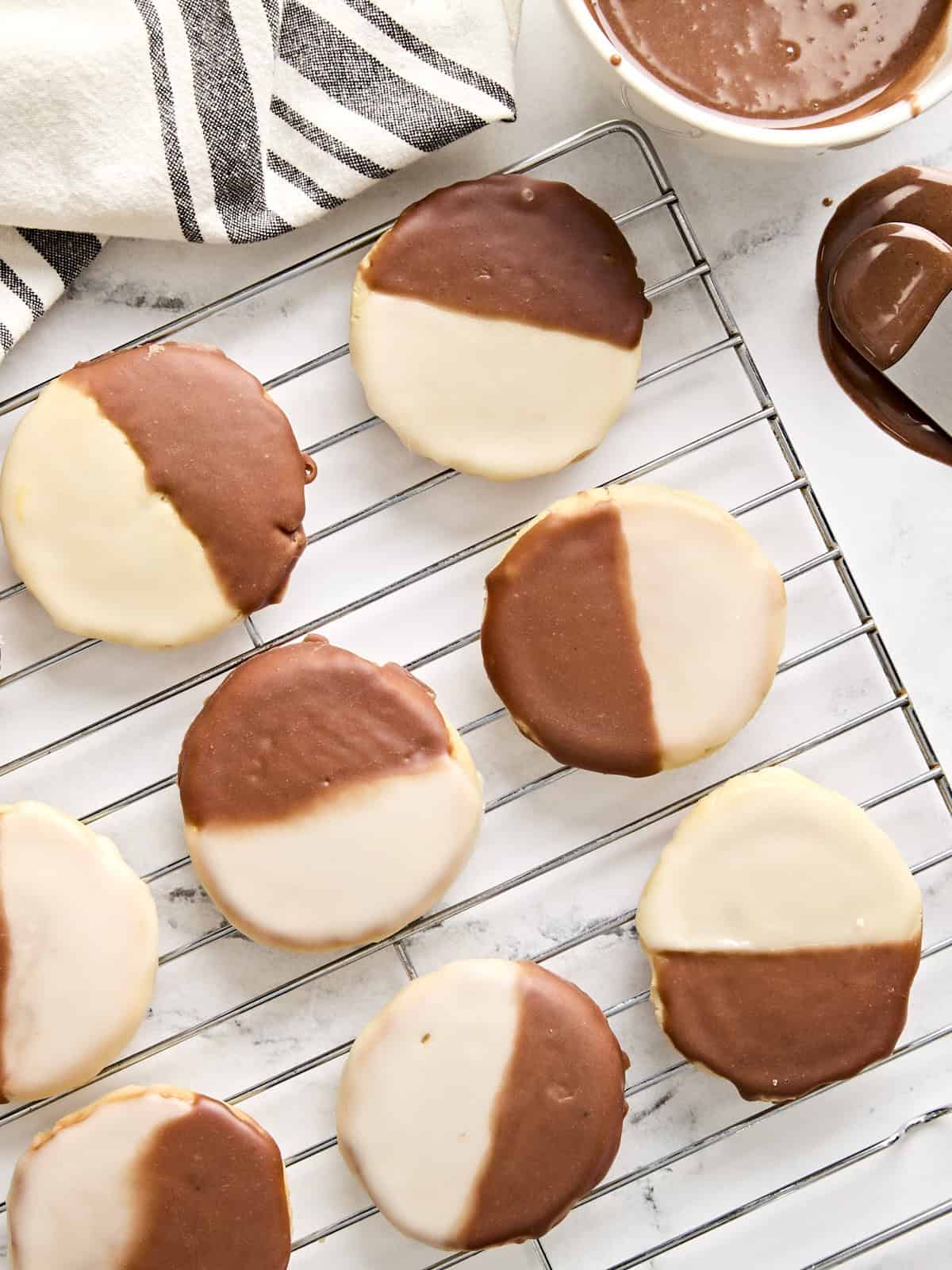 Overhead view of black and white cookies on a wire rack.