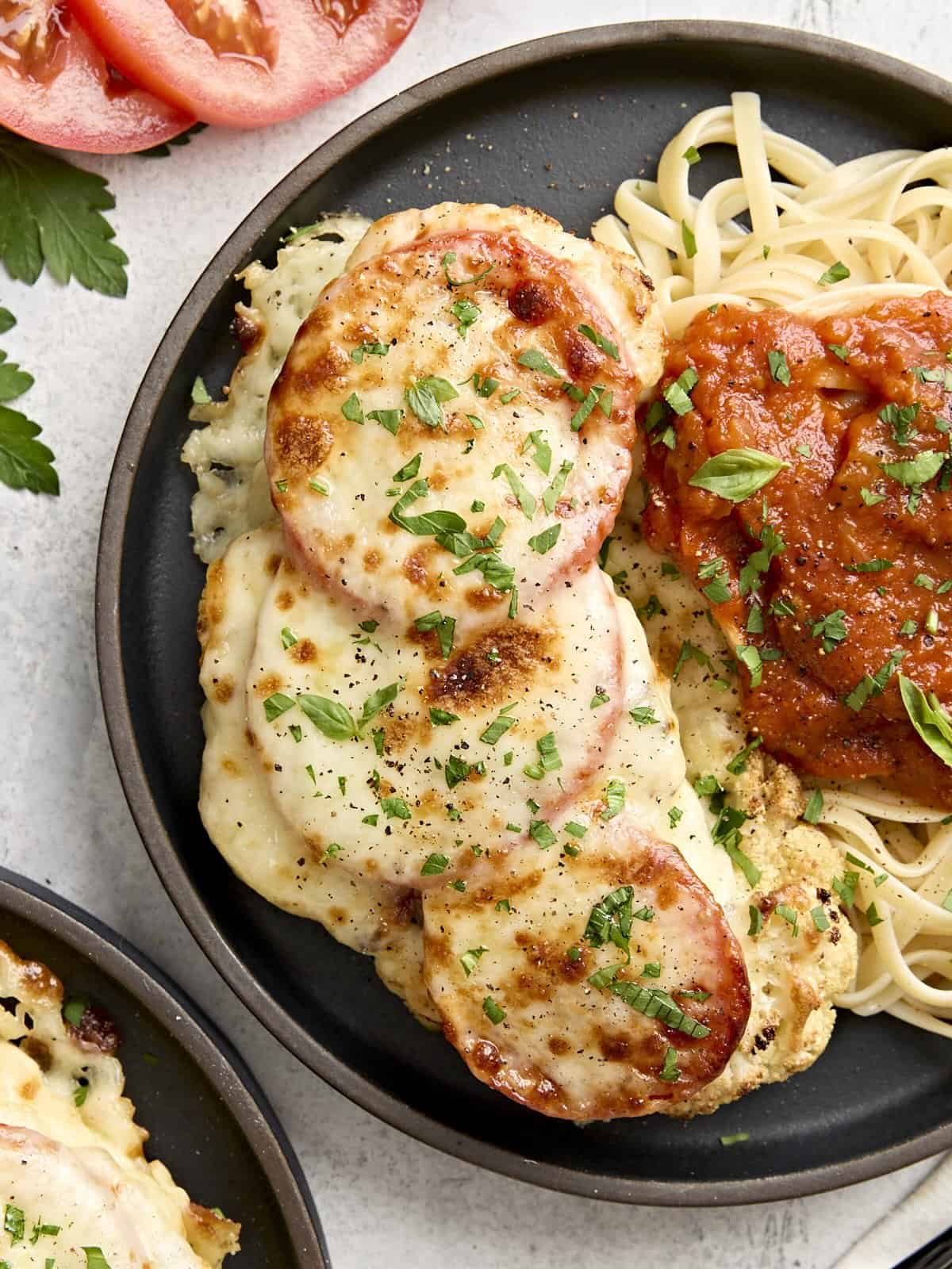 Overhead view of cauliflower parmesan on a plate with noodles and marinara sauce.