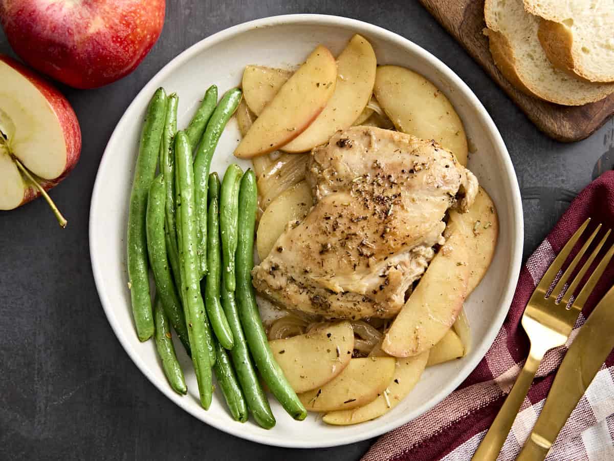 Overhead view of chicken and apples skillet dinner on a plate with green beans.