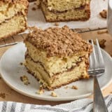 Side view of a slice of coffee cake on a plate with a fork.