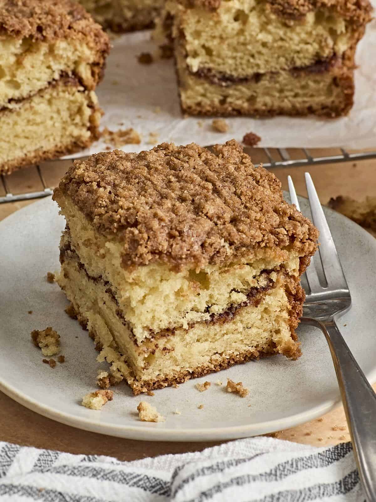 Side view of a slice of coffee cake on a plate with a fork.