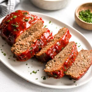 Side view of homemade meatloaf slices on a white platter.