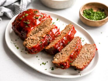 Side view of homemade meatloaf slices on a white platter.