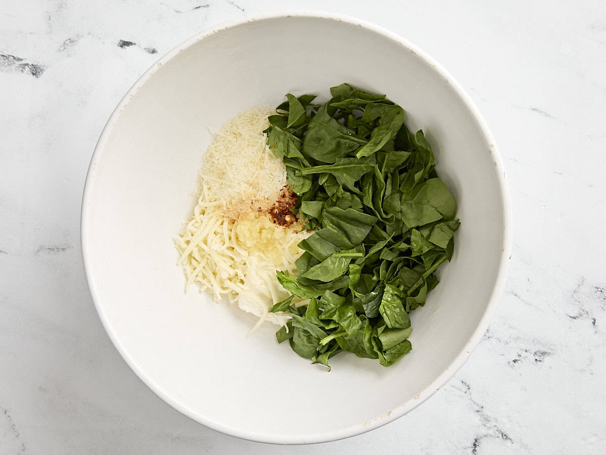 Spinach, cream cheese, parmesan, mozzarella, and seasonings in a mixing bowl.