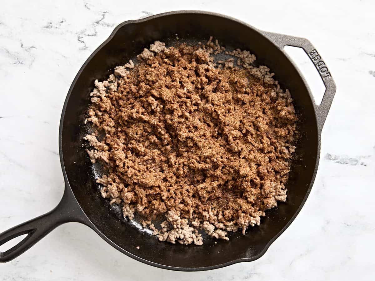 Fajita seasoning added to browned ground beef in a skillet.