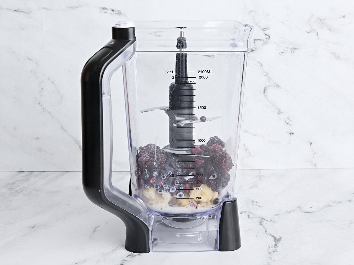 Side view of a blender with the ingredients for smoothie bowls added.