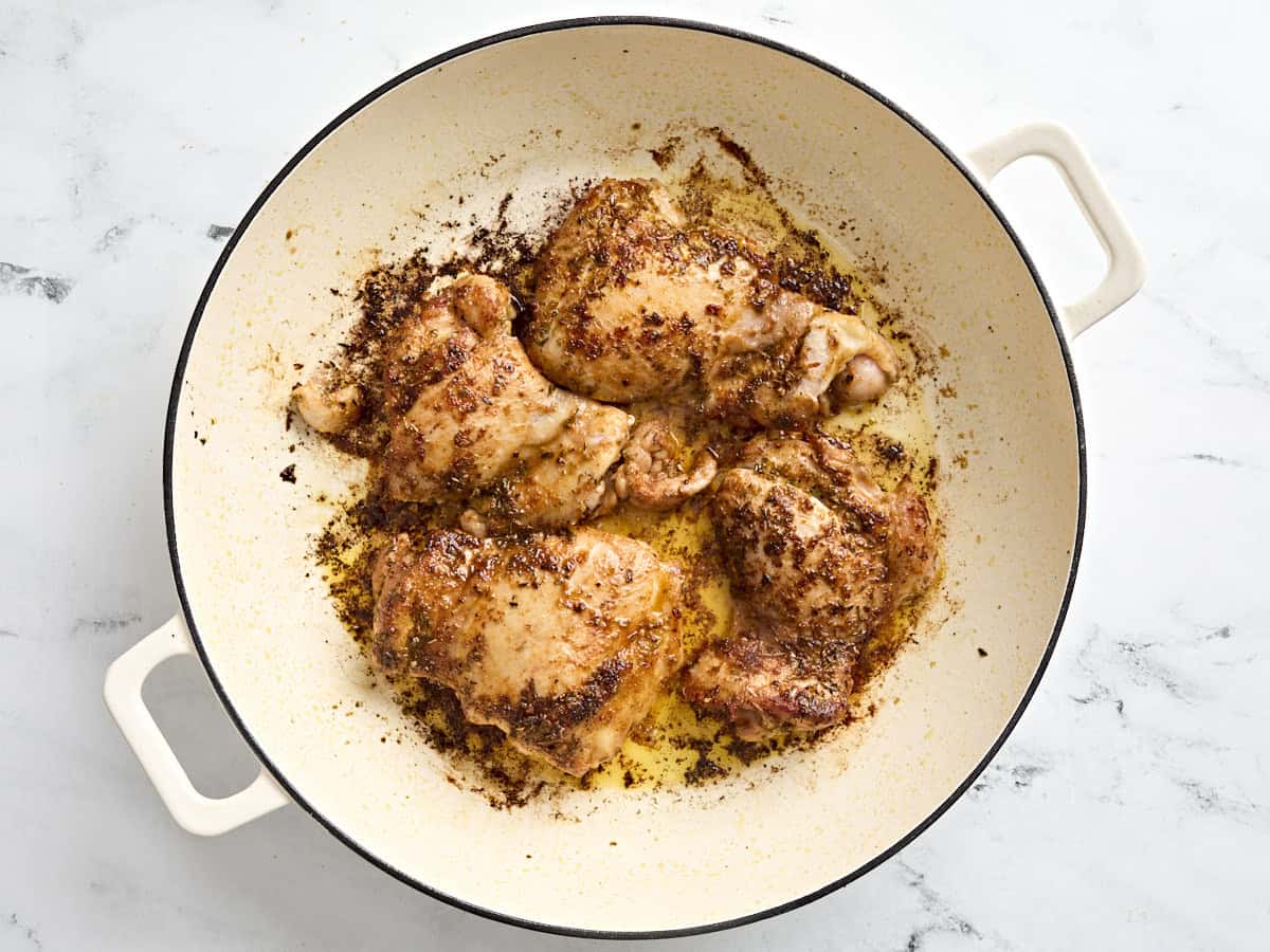 Greek chicken cooking in a skillet.