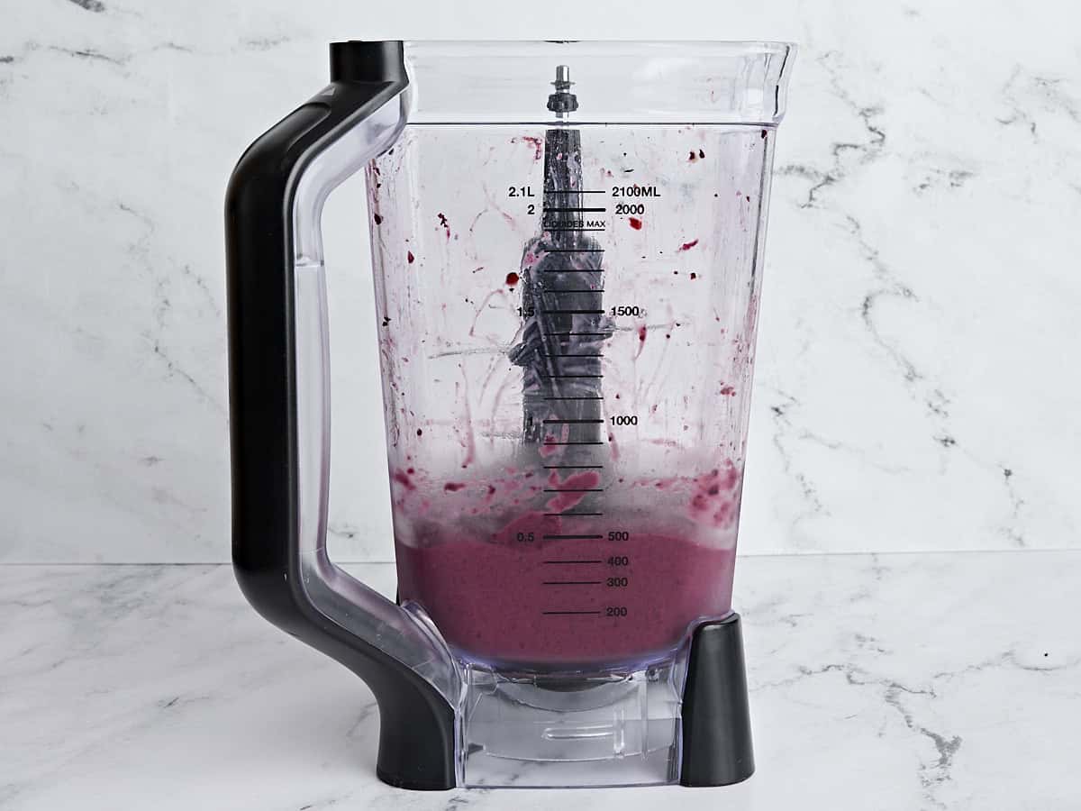 Side view of a blender holding the smoothie filling for smoothie bowls fully blended.