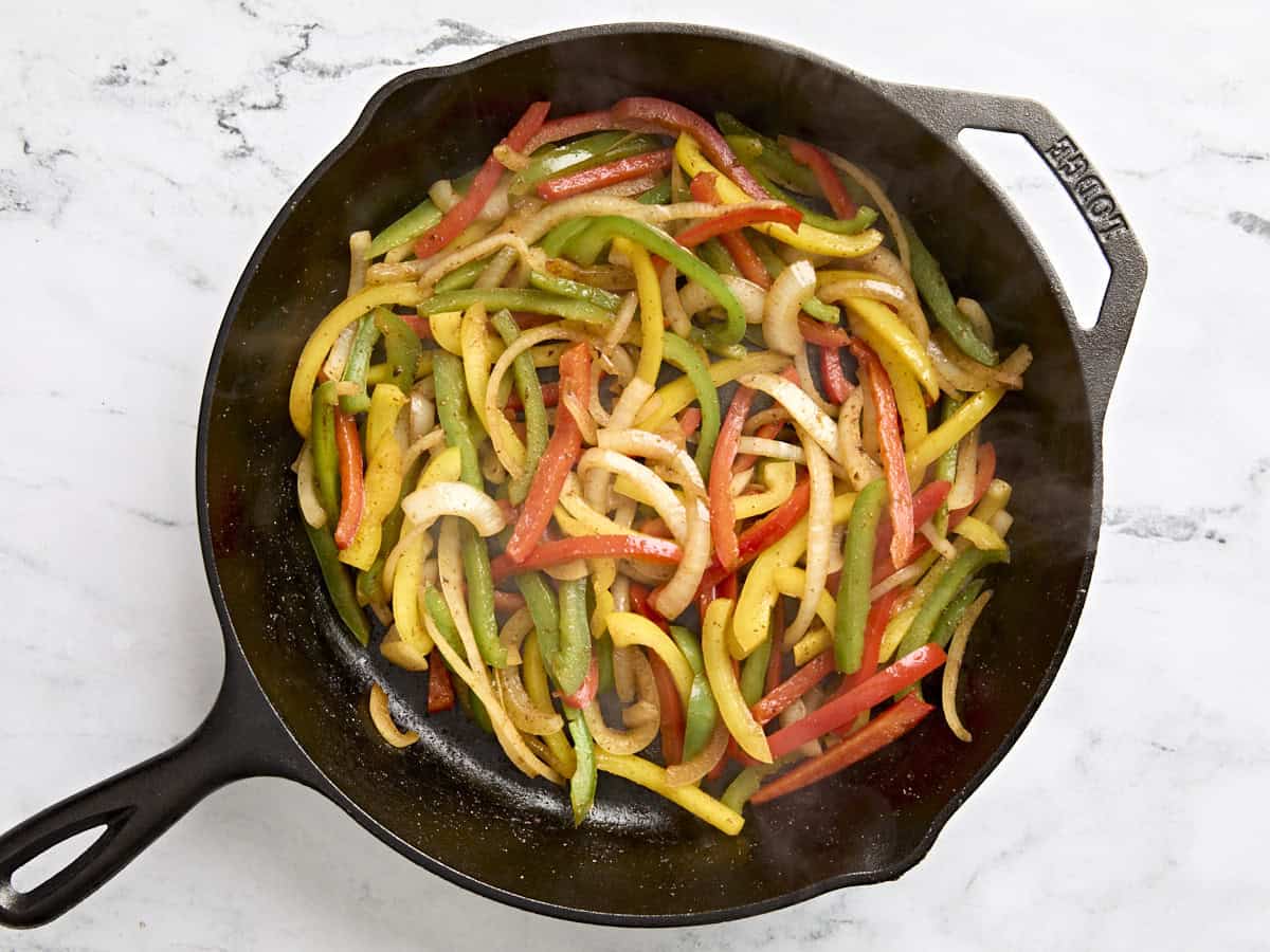 Overhead view of cooked sliced peppers in a skillet.