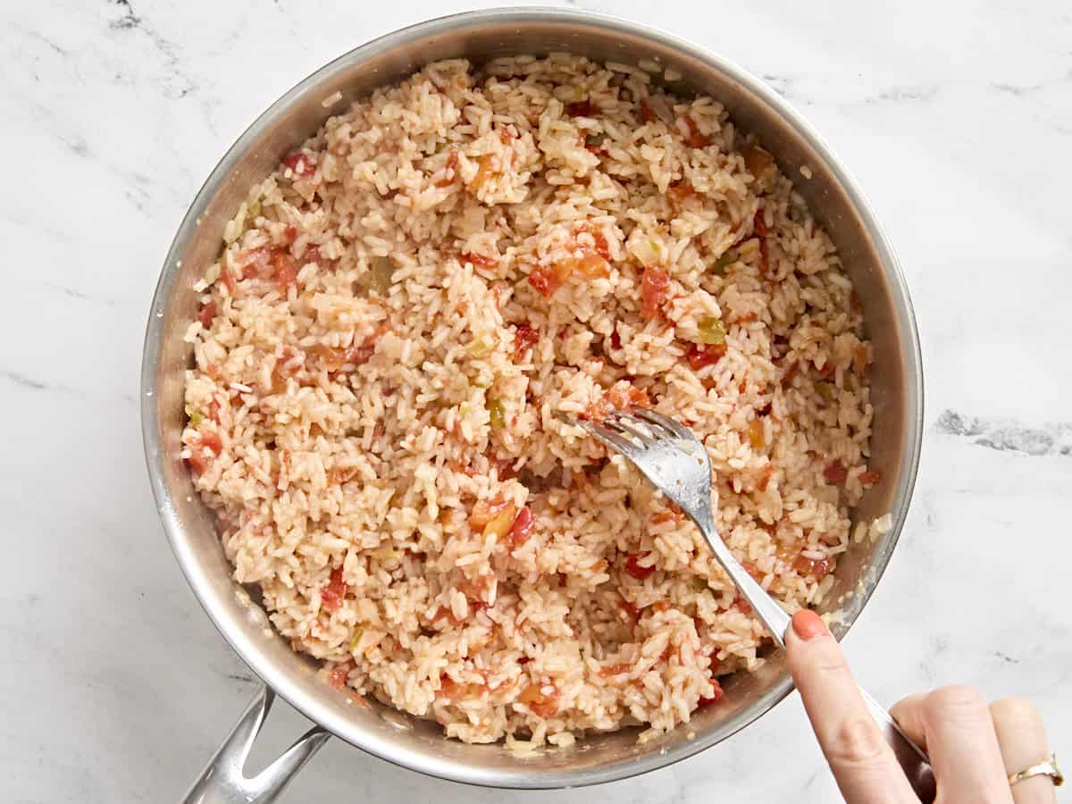 A fork fluffing up a skillet of spanish rice.