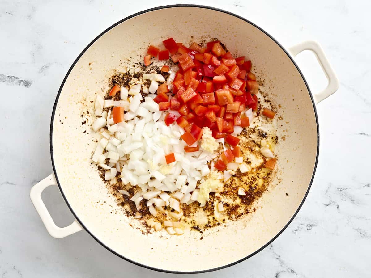 Diced bell pepper and onion added to a skillet.