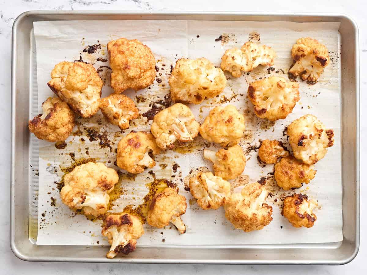 Buffalo cauliflower wings on a baking sheet halfway through cooking.