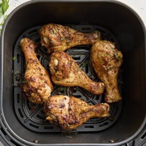 Overhead view of air fried chicken drumsticks in an air fryer basket.