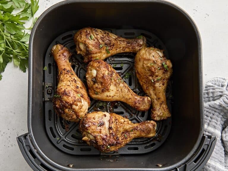 Overhead view of air fried chicken drumsticks in an air fryer basket.