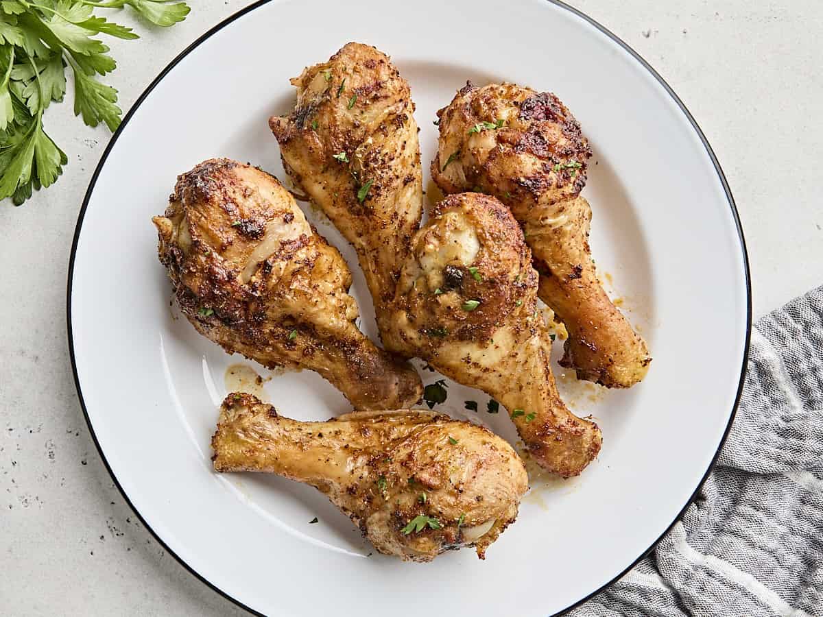 Overhead view of air fried chicken drumsticks on a plate.