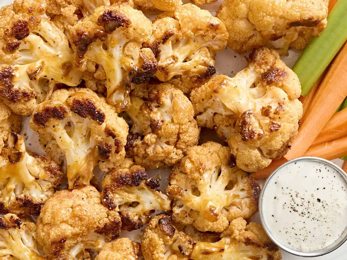 Overhead close up of buffalo cauliflower wings, carrot sticks, celery sticks, and ranch dressing.