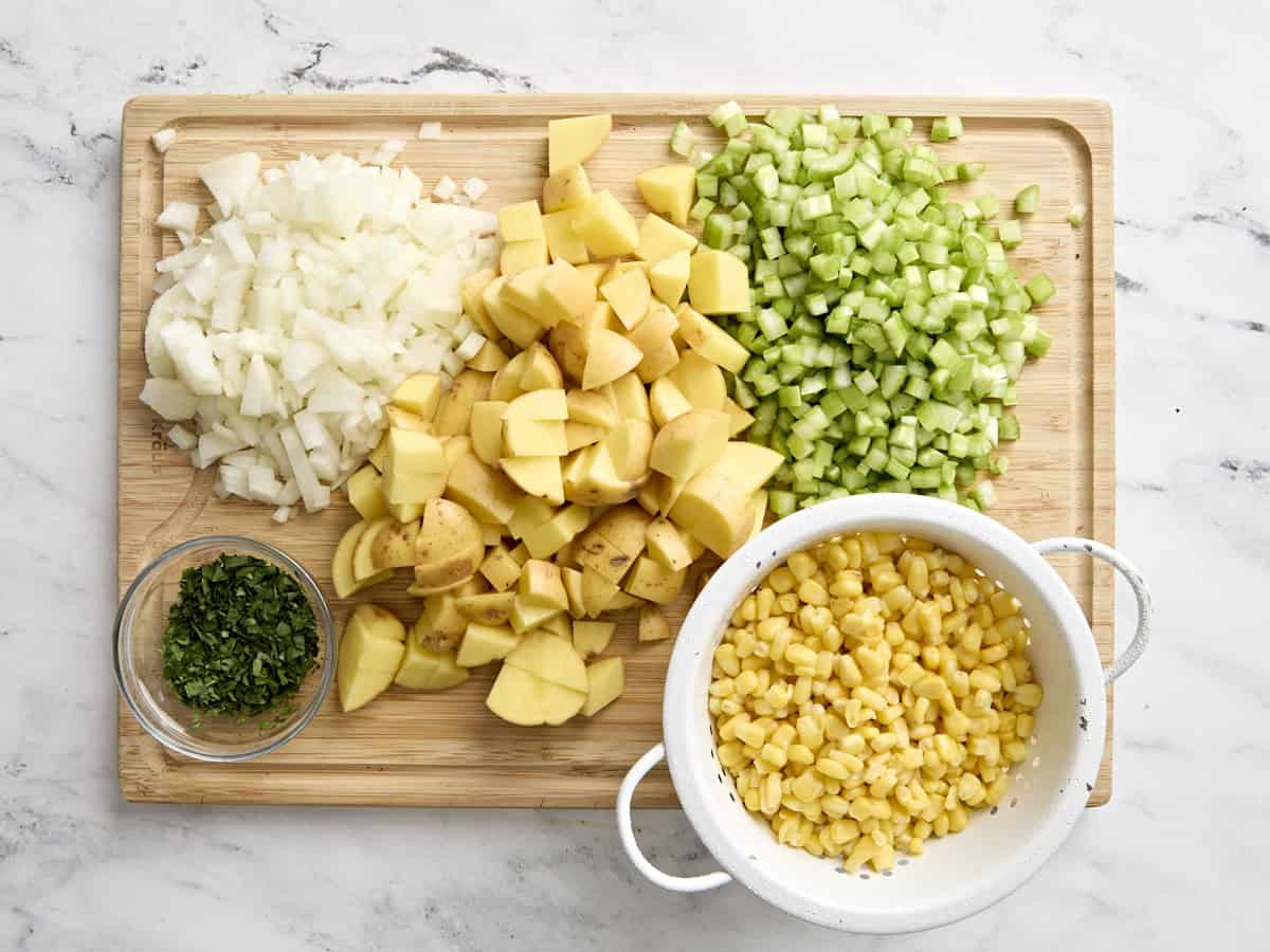 The ingredients for potato and corn chowder on a wooden cutting board.