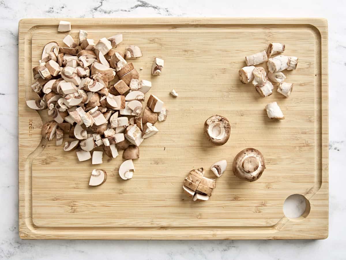 Diced mushrooms on a wooden cutting board.