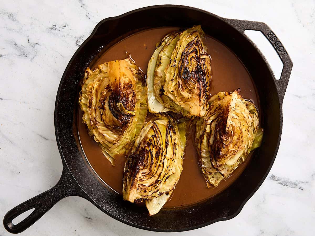 Cabbage steaks with gravy in a cast iron skillet.