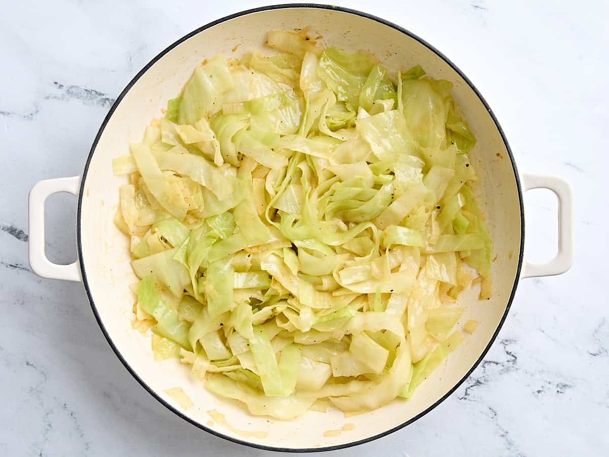 Cooked cabbage in chicken broth in a skillet.