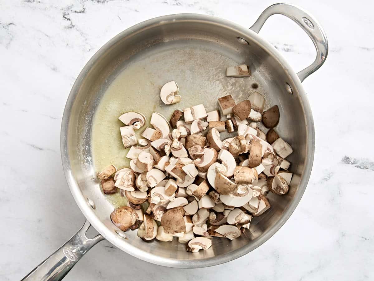 Diced mushrooms in a saute pan with melted butter.