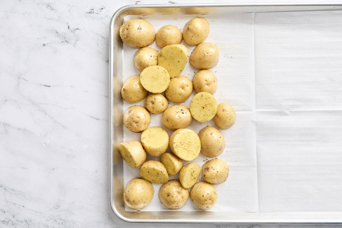 Slices Yukon gold potatoes on a parchment-lined sheet pan.