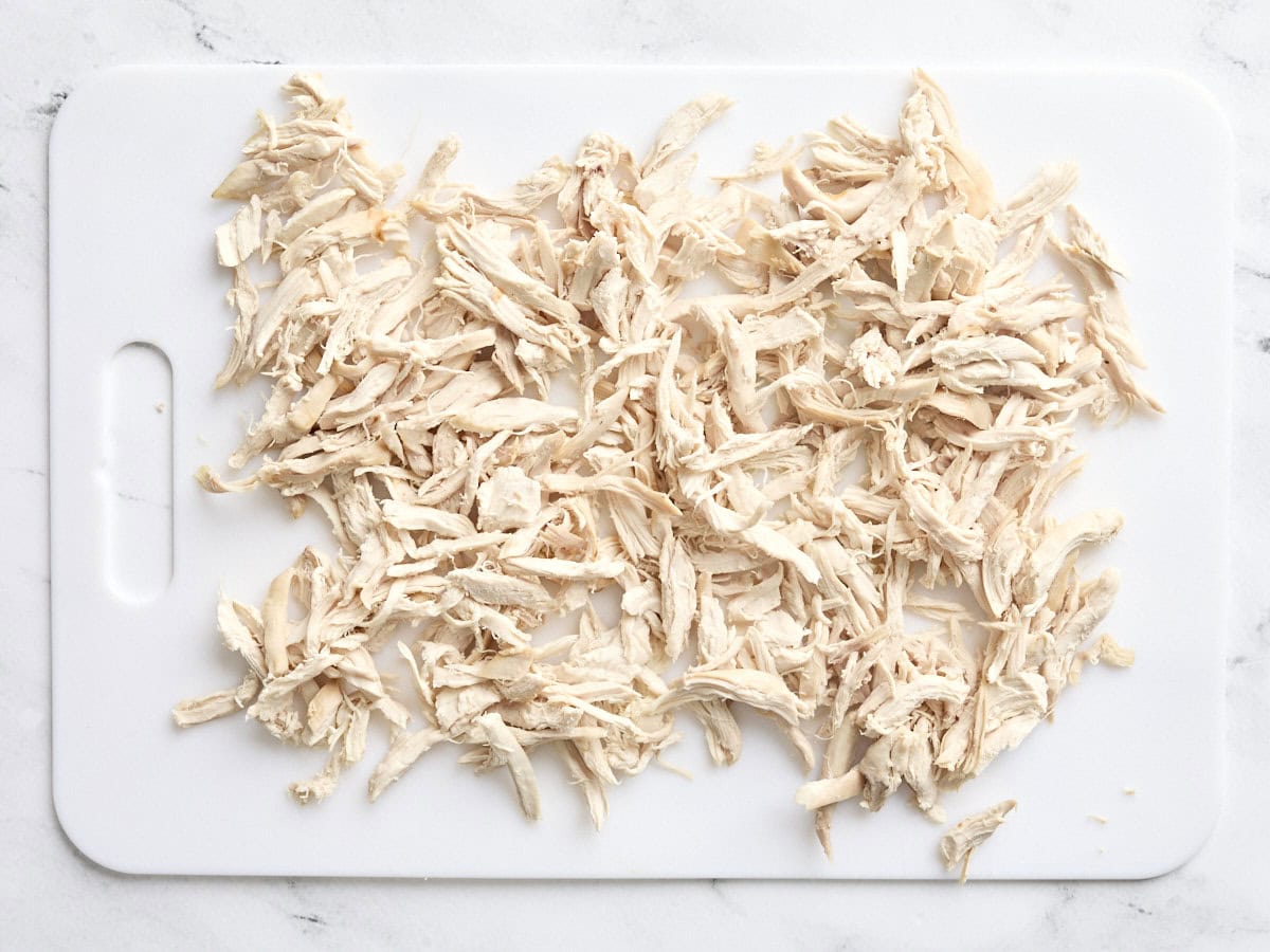 Shredded chicken on a white cutting board.