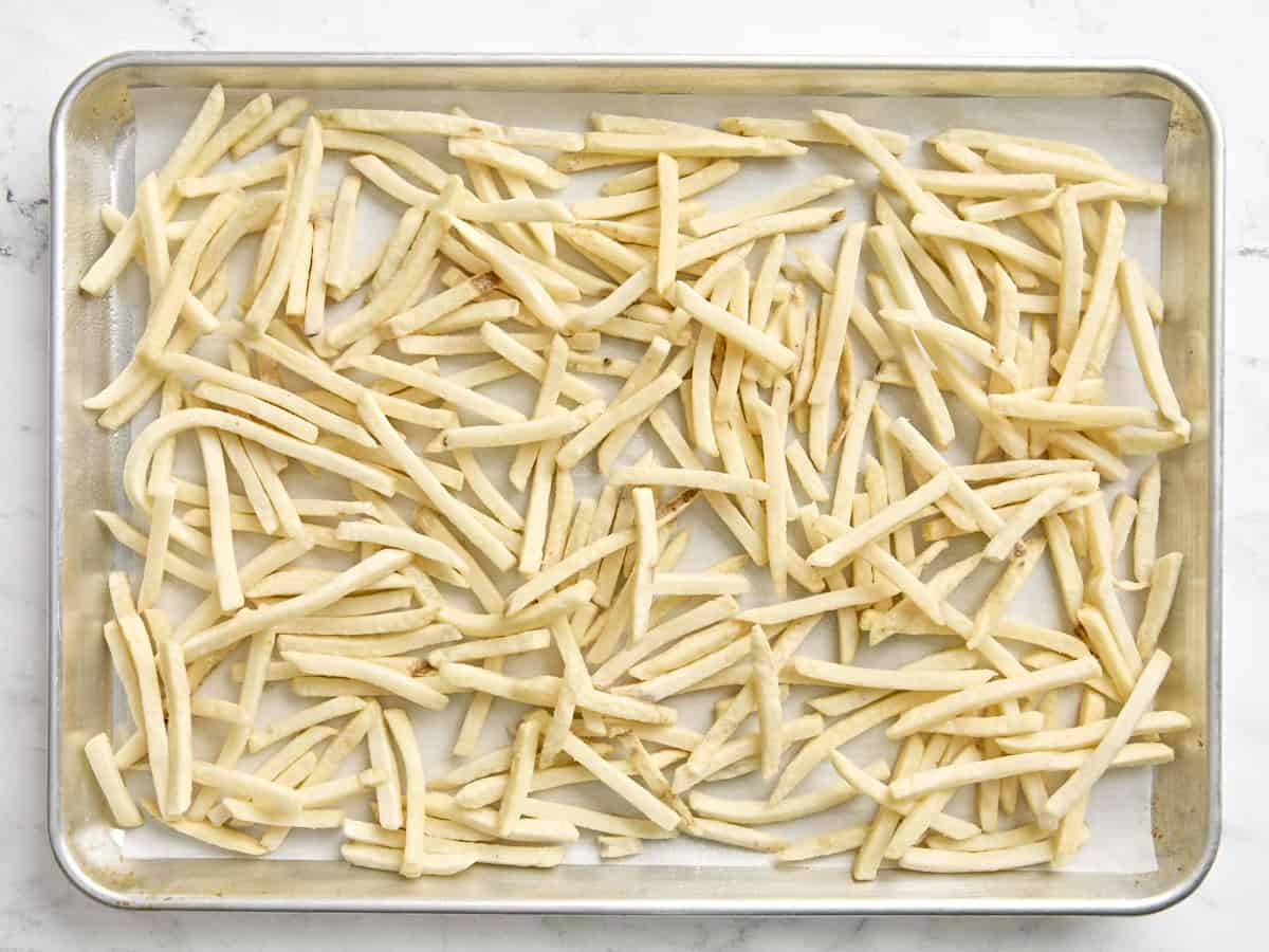 Frozen French fries on a baking sheet.