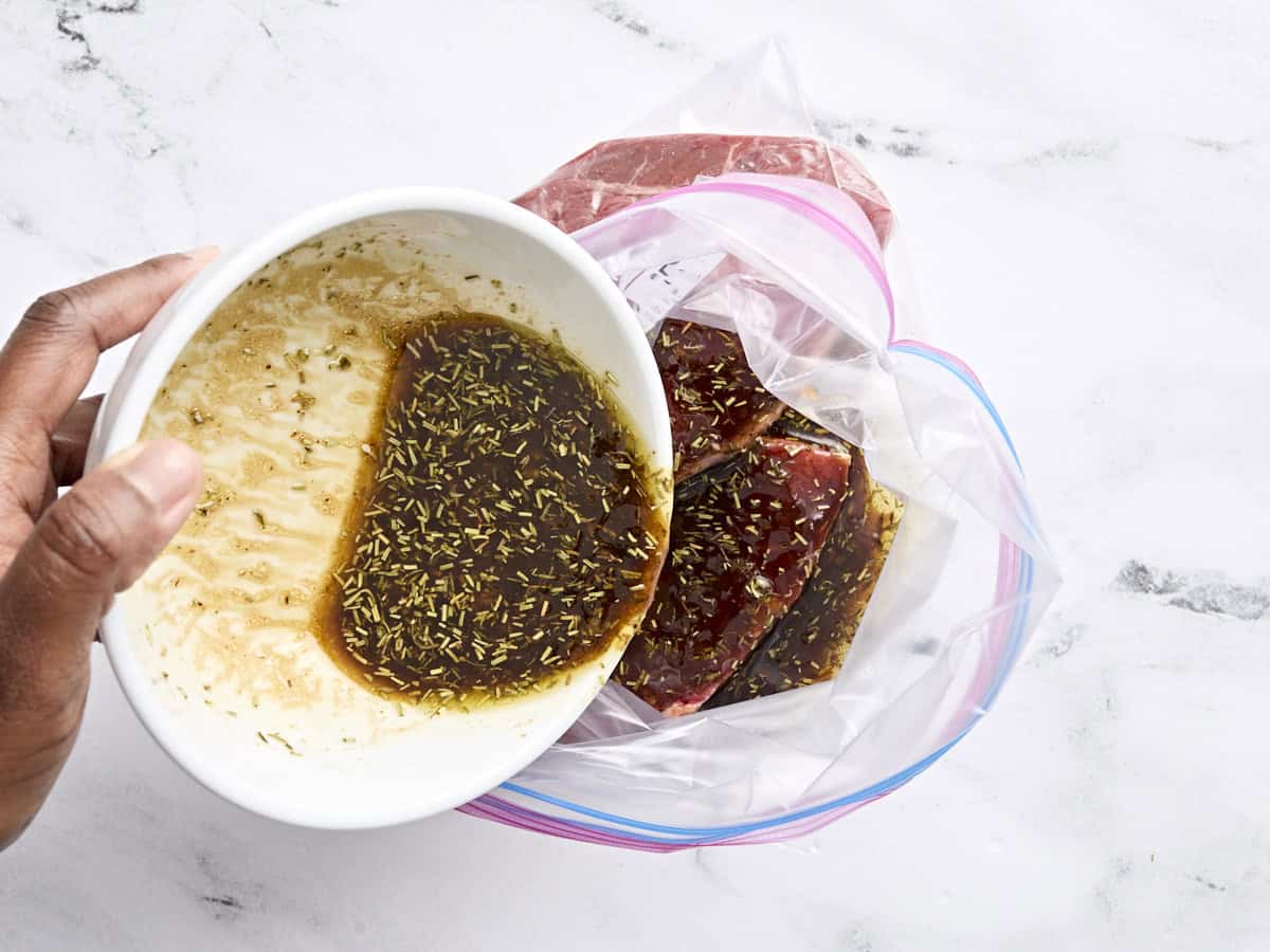 Steak marinade being poured into a ziptop bag with steak.