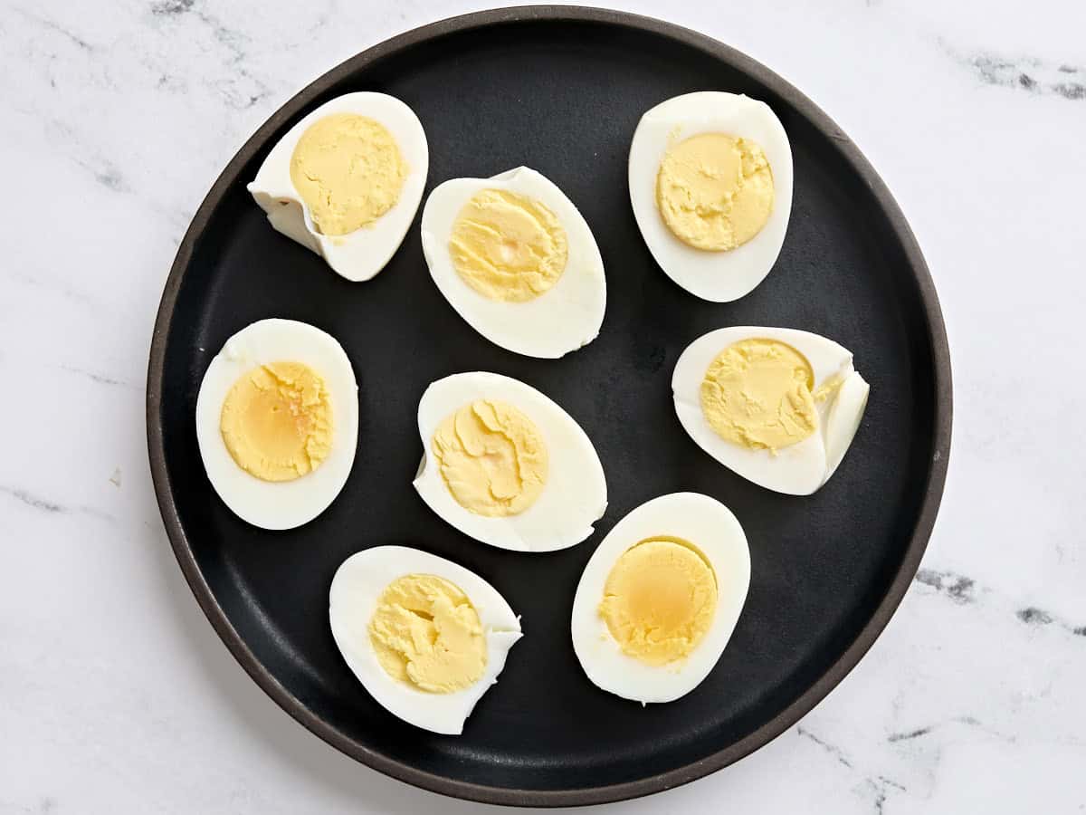 Air fryer hard boiled eggs sliced in half on a plate.