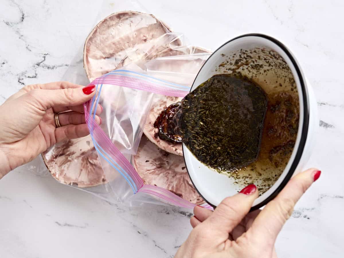 A balsamic marinade being poured into a bag of portobello mushroom caps.