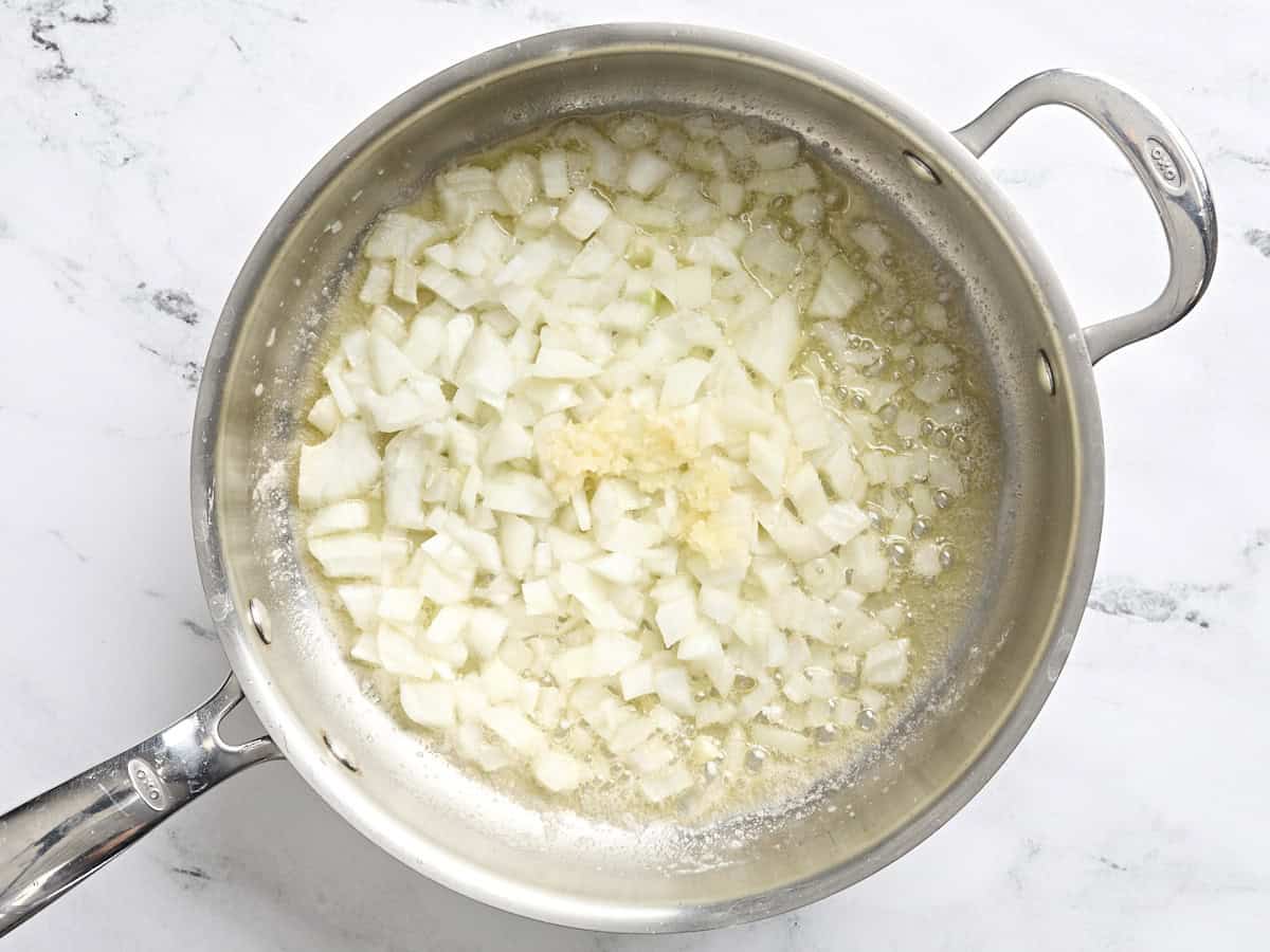 Diced onions and minced garlic sauteing in a skillet.