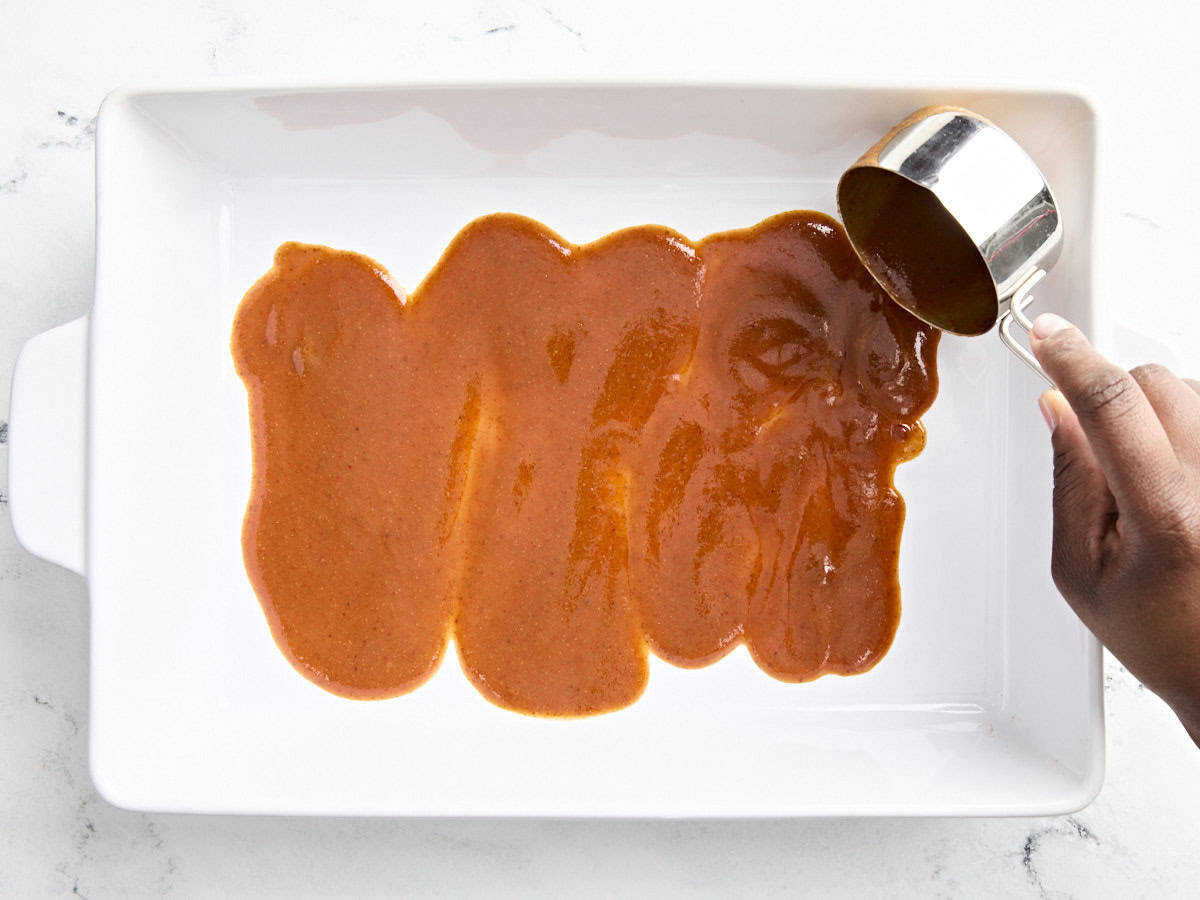 Homemade enchilada sauce added to the bottom of a baking dish.