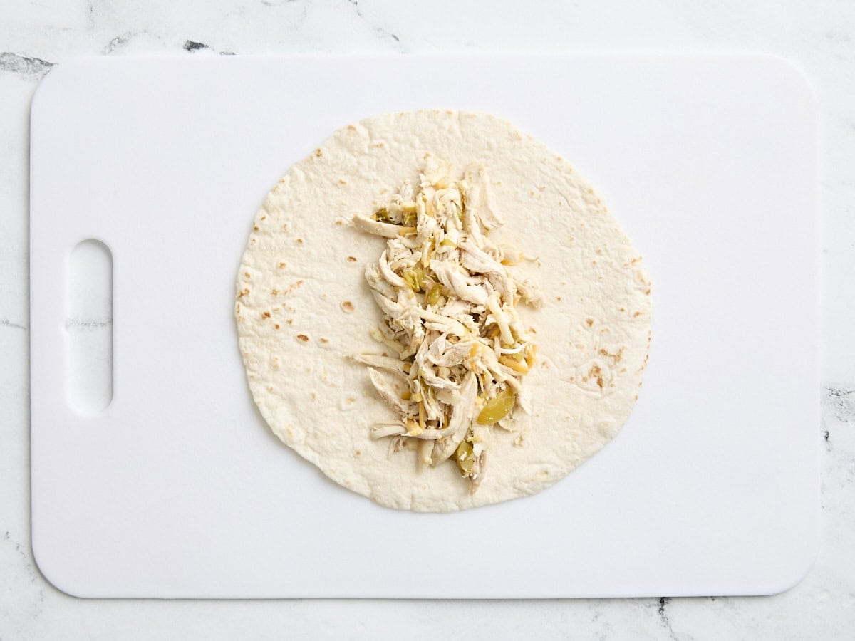 A flour tortilla topped with shredded chicken and green chili filling.