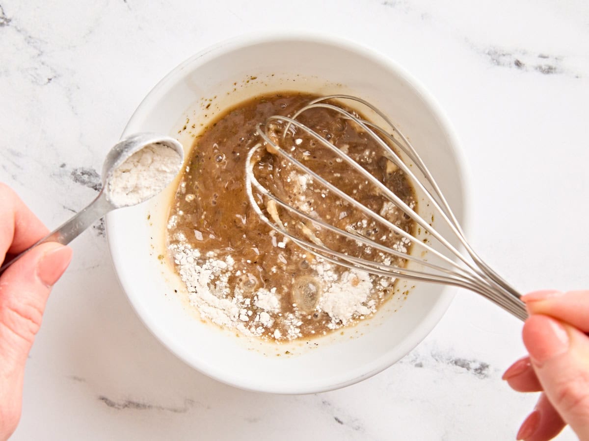 Flour and beef broth being whisked together to make a slurry.