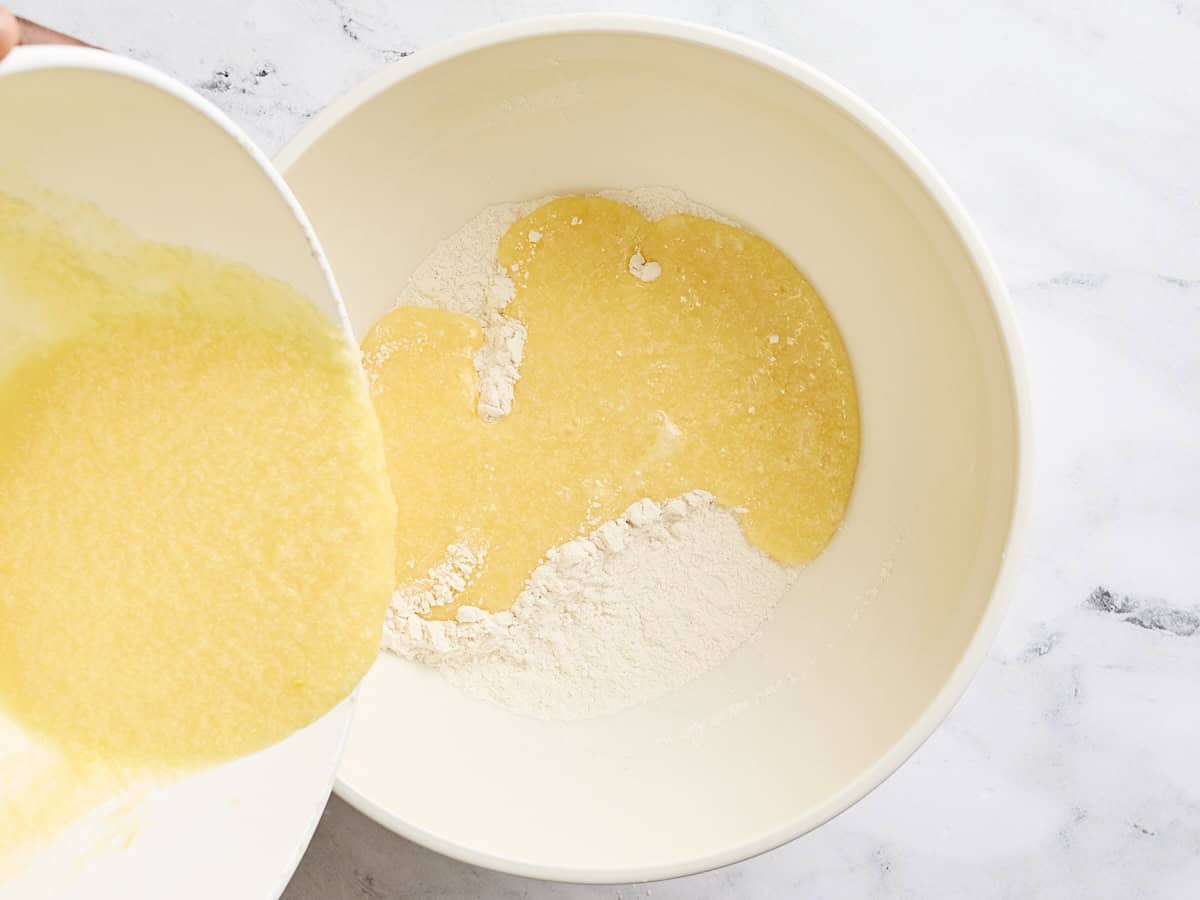 The wet ingredients for lemon blueberry muffins being poured into the dry ingredients in a bowl.