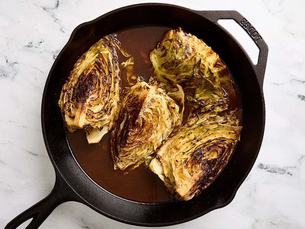 Cabbage steaks in a skillet after baking in the oven.