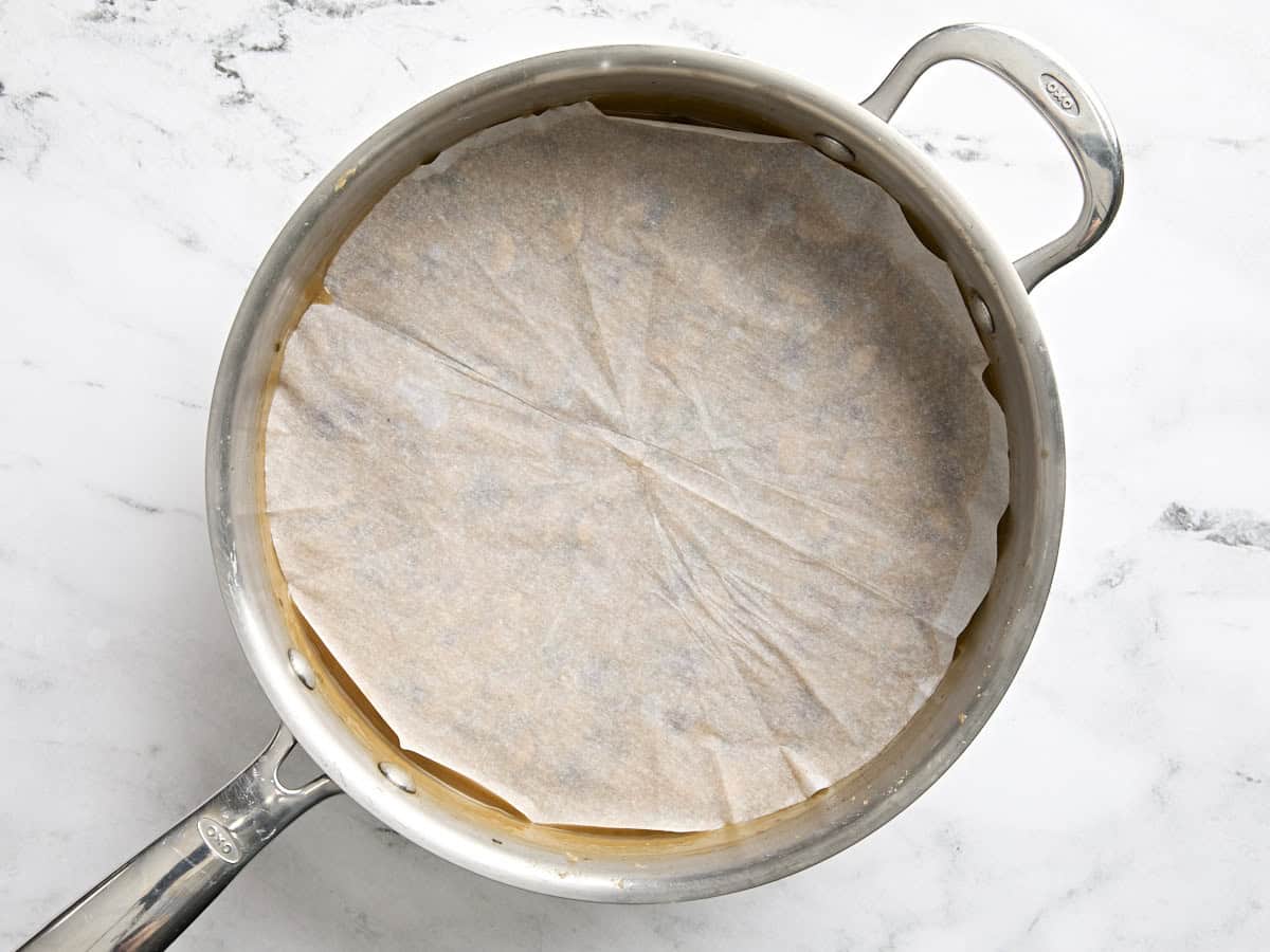 A saute pan of mushroom gravy covered with a cartouche.