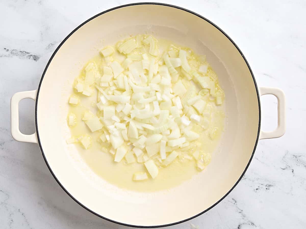 Diced onion sauteing in a skillet with olive oil and butter.