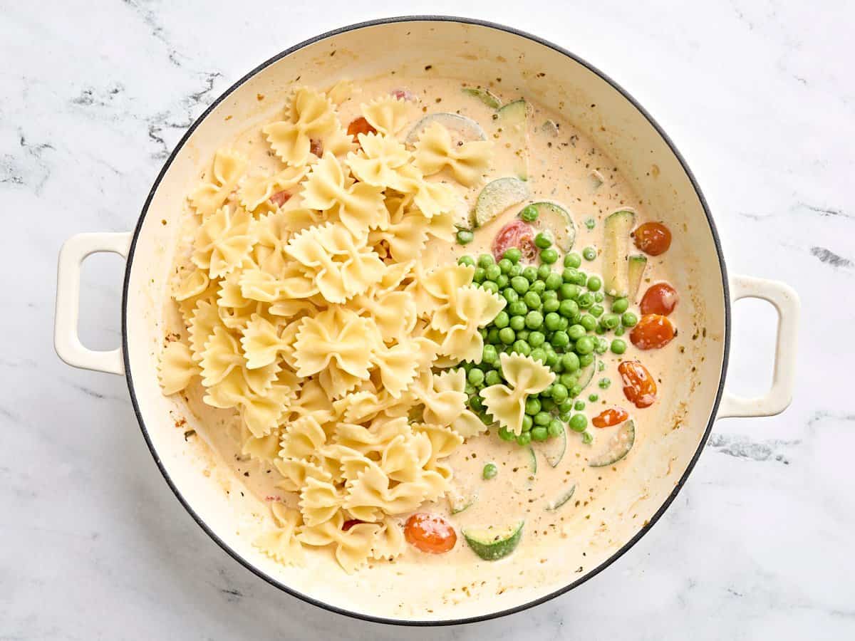 Pasta and peas added to a skillet with vegetables and a creamy sauce to make Chicken Pasta Primavera.