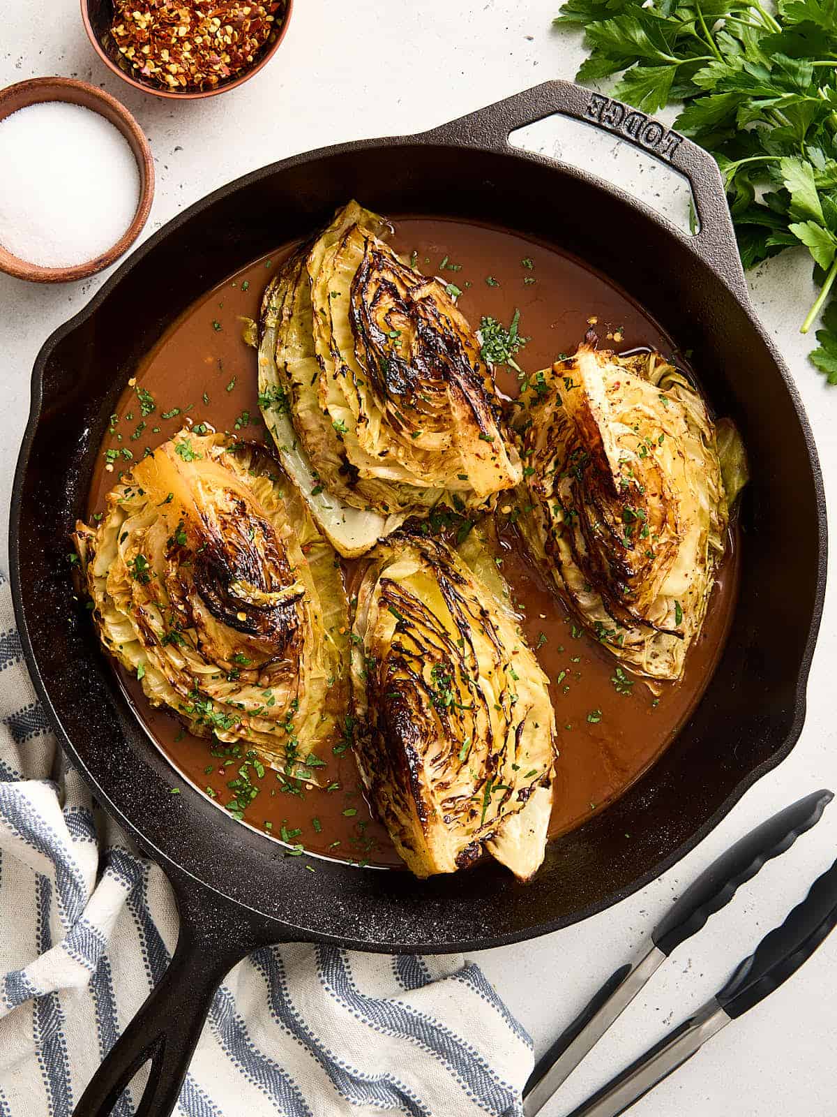 Overhead view of cabbage steaks and gravy in a cast iron skillet.