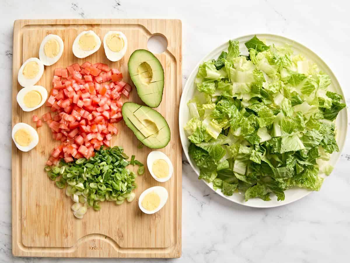 Chopped cobb salad ingredients on a cutting board and in a bowl.