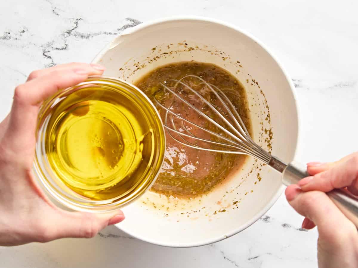 Olive oil being streamed into a homemade red wine vinaigrette.