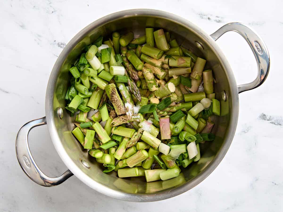 Sliced asparagus in a sauce pot with seasonings.